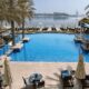 RIVA Beach Club swimming pool with palm trees overlooking Palm Jumeirah beach and Dubai skyline with Burj Al Arab view