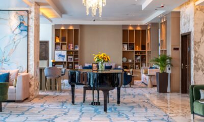 Authors' Lounge interior at voco Bonnington Dubai featuring grand piano, elegant seating, bookshelves, and crystal chandeliers