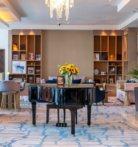 Authors' Lounge interior at voco Bonnington Dubai featuring grand piano, elegant seating, bookshelves, and crystal chandeliers
