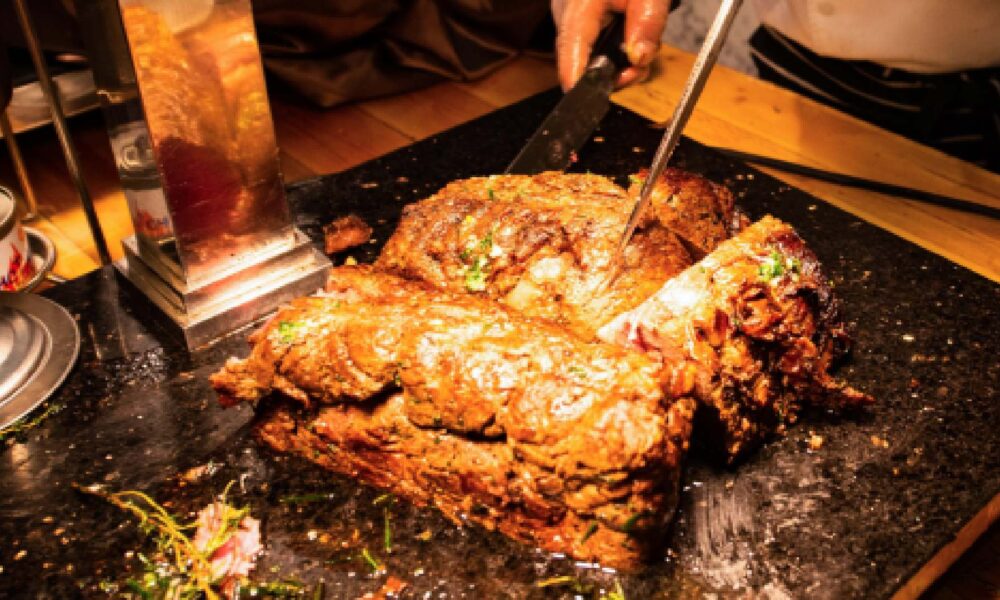 Chef cooking marinated meat and vegetables on a flat-top grill at a teppanyaki restaurant