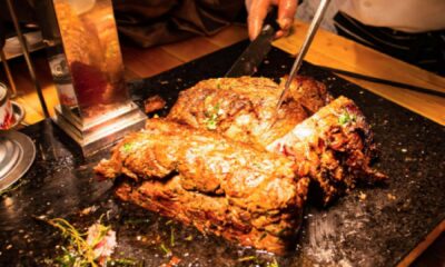 Chef cooking marinated meat and vegetables on a flat-top grill at a teppanyaki restaurant