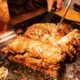 Chef cooking marinated meat and vegetables on a flat-top grill at a teppanyaki restaurant