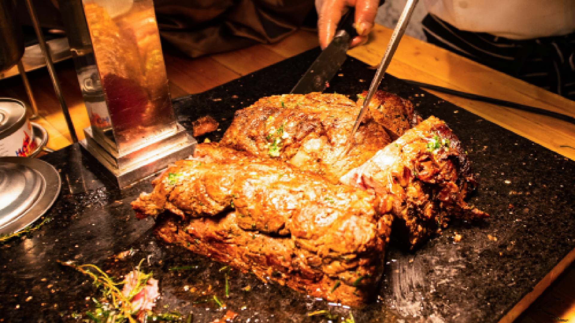Chef cooking marinated meat and vegetables on a flat-top grill at a teppanyaki restaurant