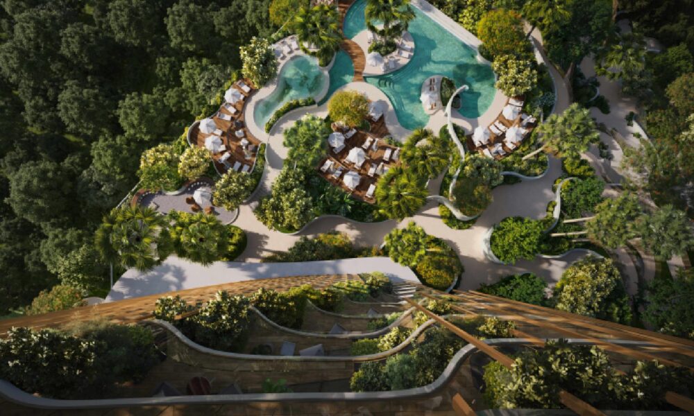 An aerial rendering shows a lush, green residential complex surrounded by forest, featuring terraced balconies covered in plants and a large, free-form swimming pool with sunbeds and white umbrellas.