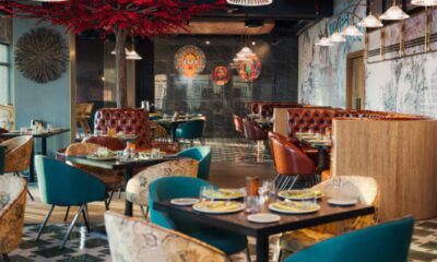 Rohini restaurant interior at Mövenpick JLT featuring colorful seating, Indian artwork, decorative tree, and modern dining ambiance