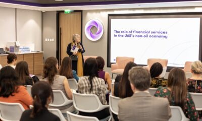 A group of three women and one man, formally dressed, are standing in front of a backdrop featuring the logos of Heriot-Watt University and Grant Thornton at a press event.