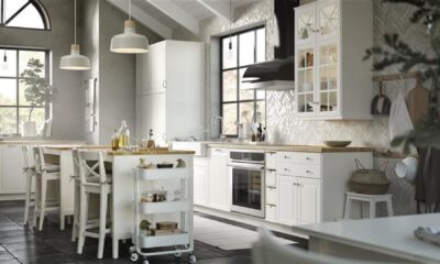 Modern Scandinavian-style kitchen with white cabinets, gray walls, pendant lighting, herringbone backsplash, and a central island with wooden countertop