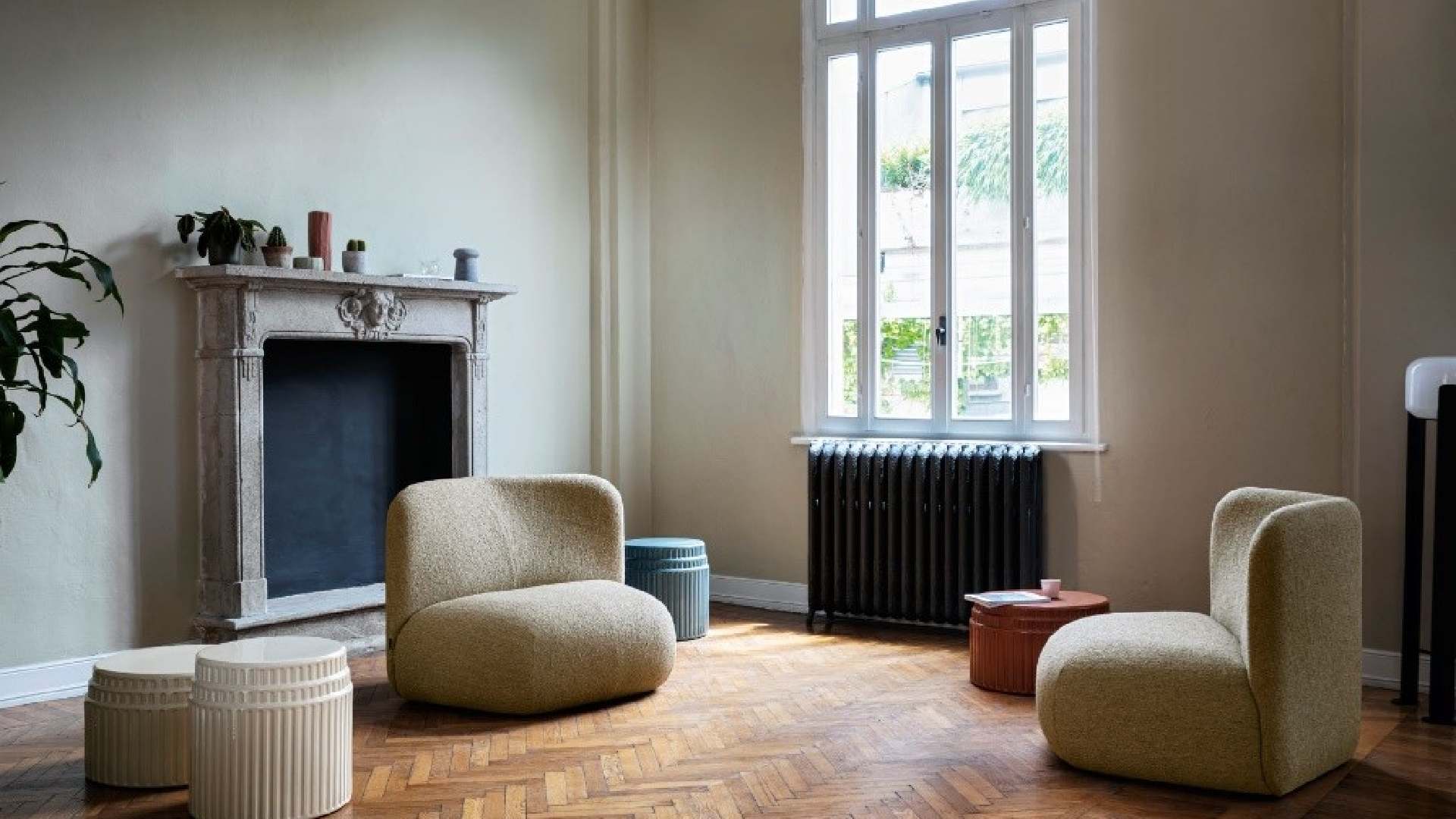 A modern living room features a large, dark brown leather sofa with a chaise lounge, light wood flooring, and a glass-topped coffee table, with a partial view of a dining area in the background.