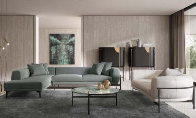 A modern, minimalist home office space features a light wood desk, a laptop, and various office supplies neatly arranged, with a white swivel chair and natural light entering from the side.