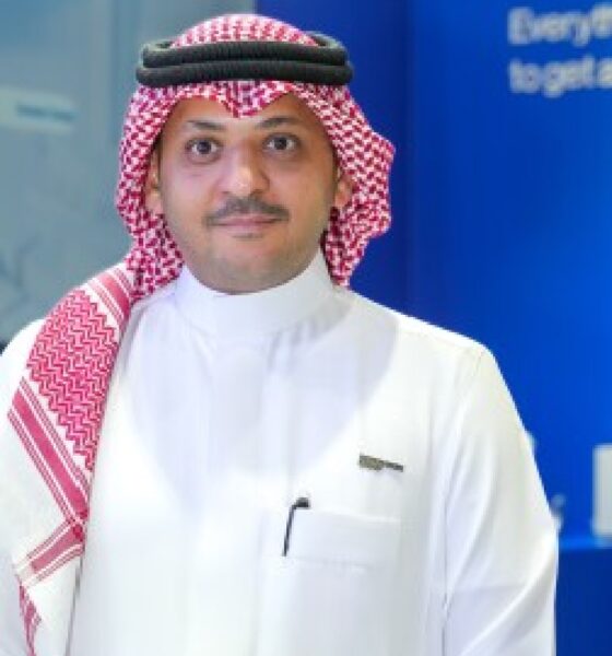 An elegantly set dining room features a modern wooden table, comfortable grey upholstered chairs, a decorative white console table, and abstract wall art, all under soft, ambient lighting.