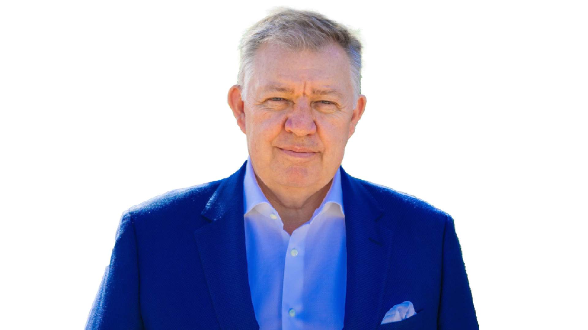 Professional headshot of a senior executive with grey hair wearing a blue blazer and light blue shirt with pocket square against a white background