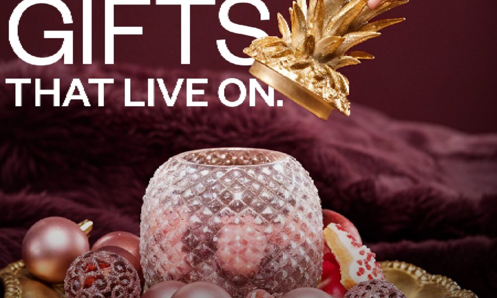 A round, modern dining table set with white tableware and wine glasses, surrounded by light-colored, curved dining chairs, all illuminated by a large, minimalist pendant light.