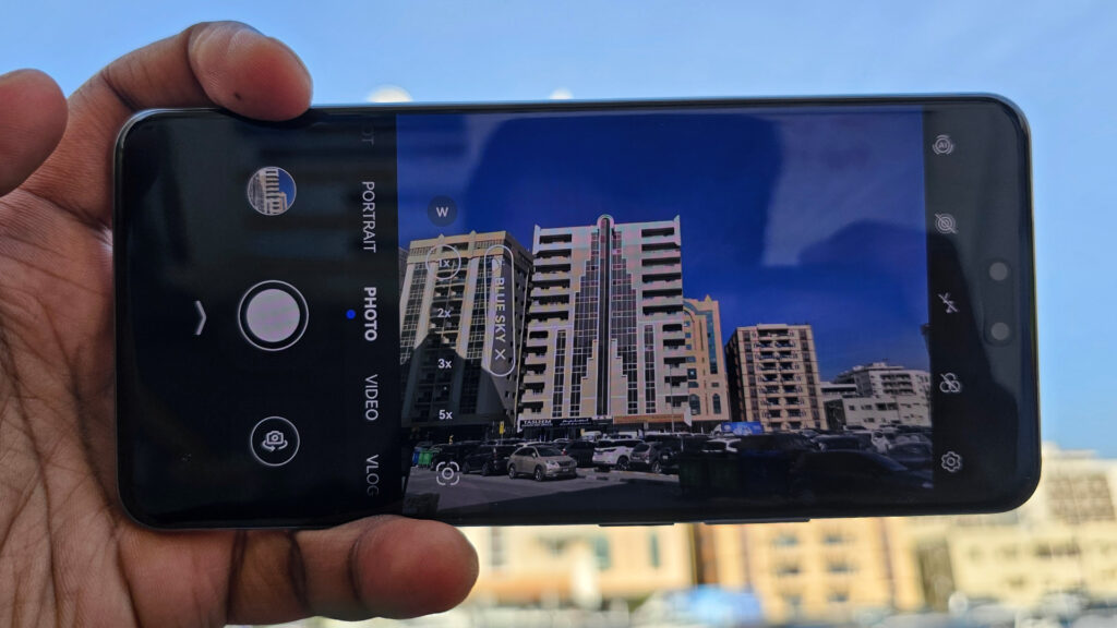 A person holding the Huawei Nova 14 Pro, displaying the camera app interface with building photos.