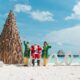 A professional lifestyle photograph at Nova Maldives during the 'Maldivian Magic' festive season, featuring a unique sustainable Christmas tree handcrafted from tiered cajon wood and driftwood.
