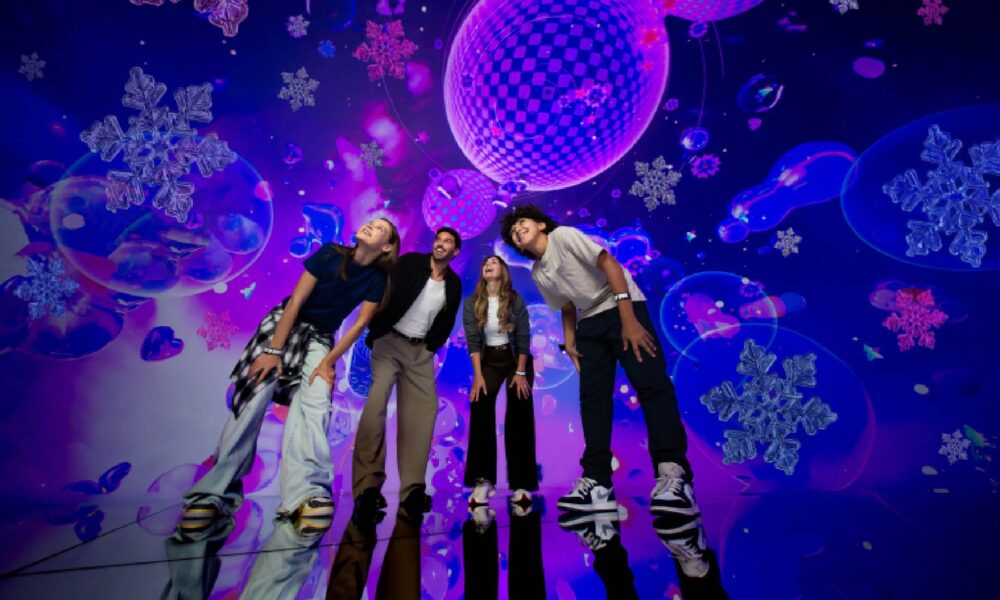 A colorful, immersive indoor space at House of Hype featuring glowing, stylized Christmas trees and festive light installations