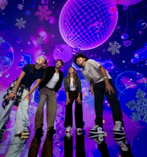 A colorful, immersive indoor space at House of Hype featuring glowing, stylized Christmas trees and festive light installations