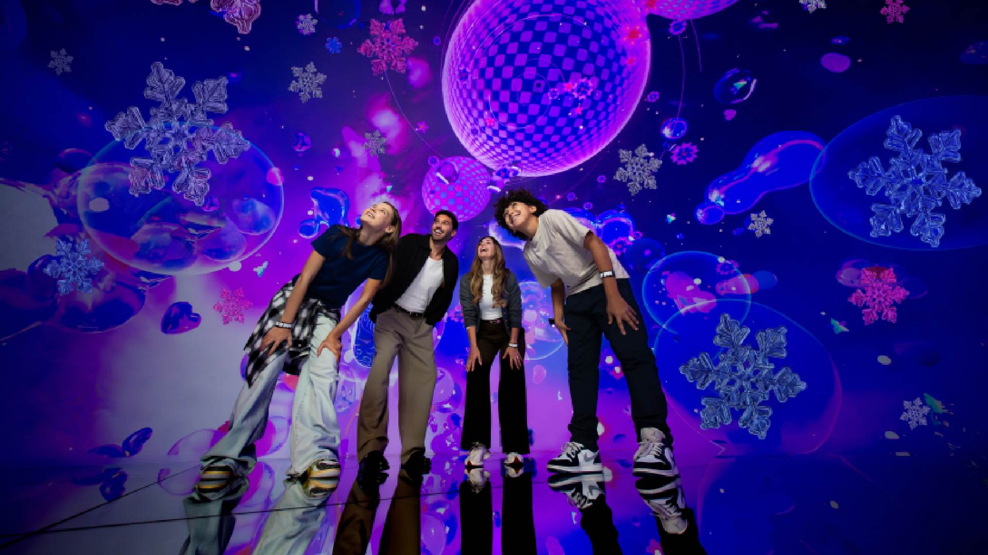 A colorful, immersive indoor space at House of Hype featuring glowing, stylized Christmas trees and festive light installations