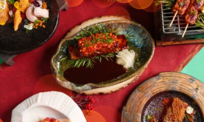 A close-up of a meticulously plated OAnjo Nikkei dish, possibly a festive tuna ceviche or tiradito, garnished with edible flowers and vibrant Peruvian accents.