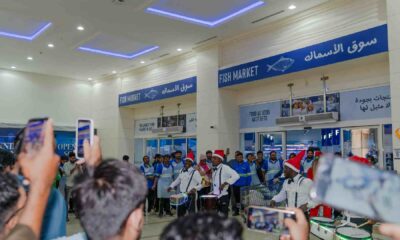 A wide-angle lifestyle photograph of the Waterfront Market Seafood Festival in Dubai, featuring a bustling promenade decorated with a unique seafood-themed festive tree.