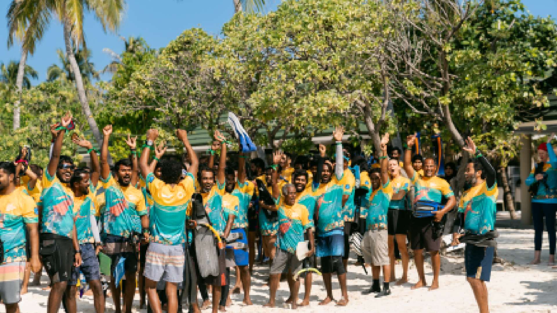 An aerial shot of hundreds of snorkelers gathered in the shallow turquoise water near the house reef at Siyam World Maldives, participating in the Guinness World Record attempt