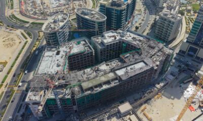 Aerial construction progress shot of the TOWNX Ashley Hills project in Arjan, Dubai, showing the multi-story concrete structure approximately 40% complete with visible construction cranes and scaffolding.