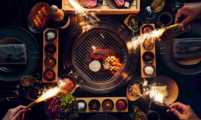 A dynamic culinary scene at Smoki Moto on Palm Jumeirah, The background shows the vibrant, party-ready interior and the al fresco terrace overlooking the Dubai skyline, embodying the 'Smoke, Soul & Seoul' festive theme
