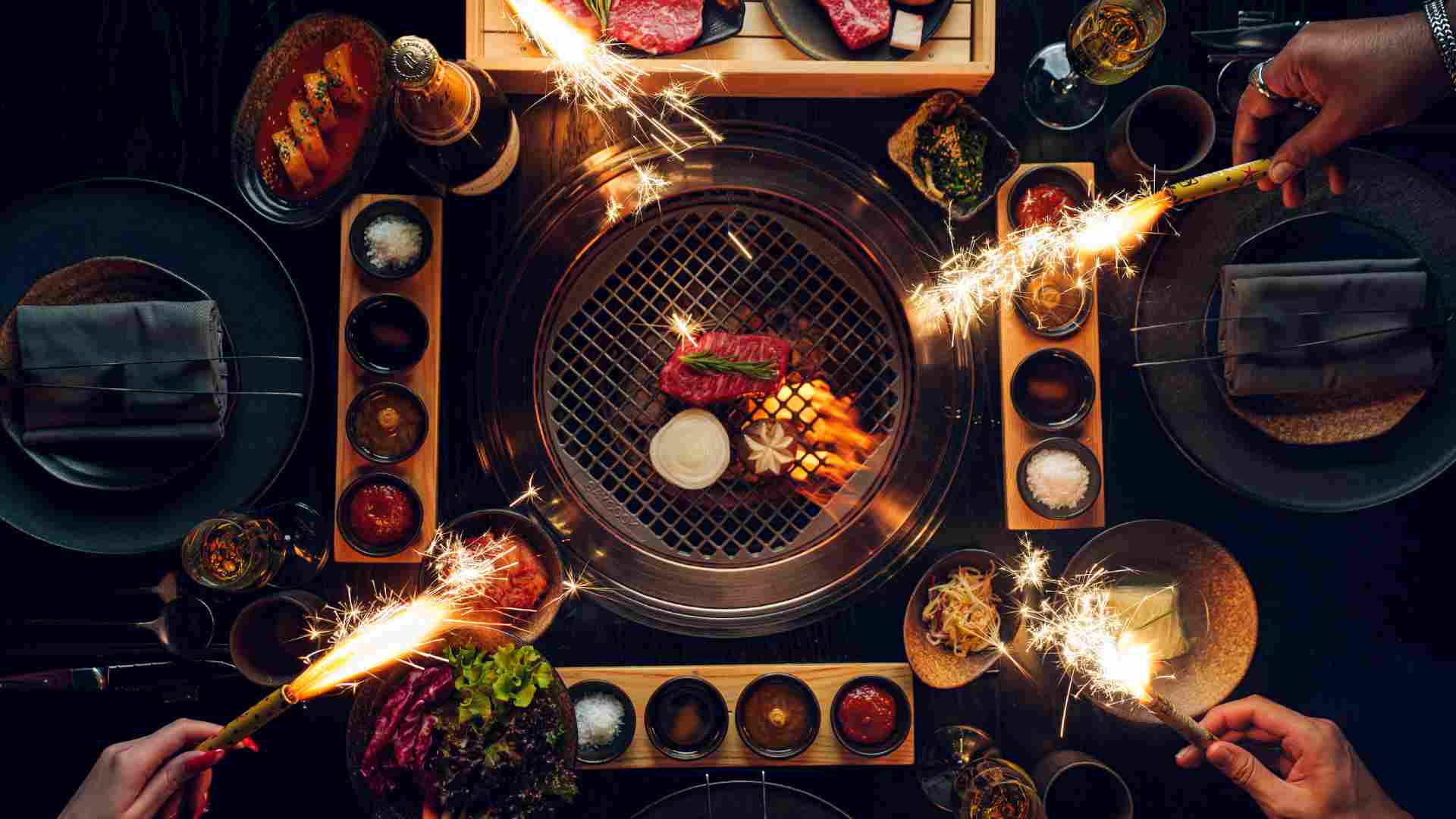 A dynamic culinary scene at Smoki Moto on Palm Jumeirah, The background shows the vibrant, party-ready interior and the al fresco terrace overlooking the Dubai skyline, embodying the 'Smoke, Soul & Seoul' festive theme