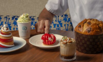 A traditional Italian Panettone cake wrapped in festive paper and ribbon, sitting on a white pedestal.