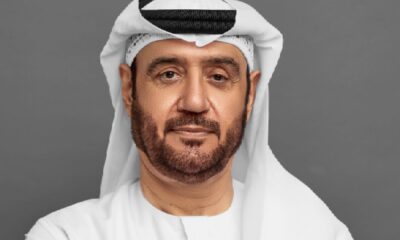 Person wearing a traditional white kandura and ghutra standing on an ornate staircase with decorative black and gold railing inside a bright, elegant interior featuring white walls and intricate architectural details. it is Abdulrahman Abdulla Alhelo Alsuwaidi Co-founder & Chairman, Nabni Developments