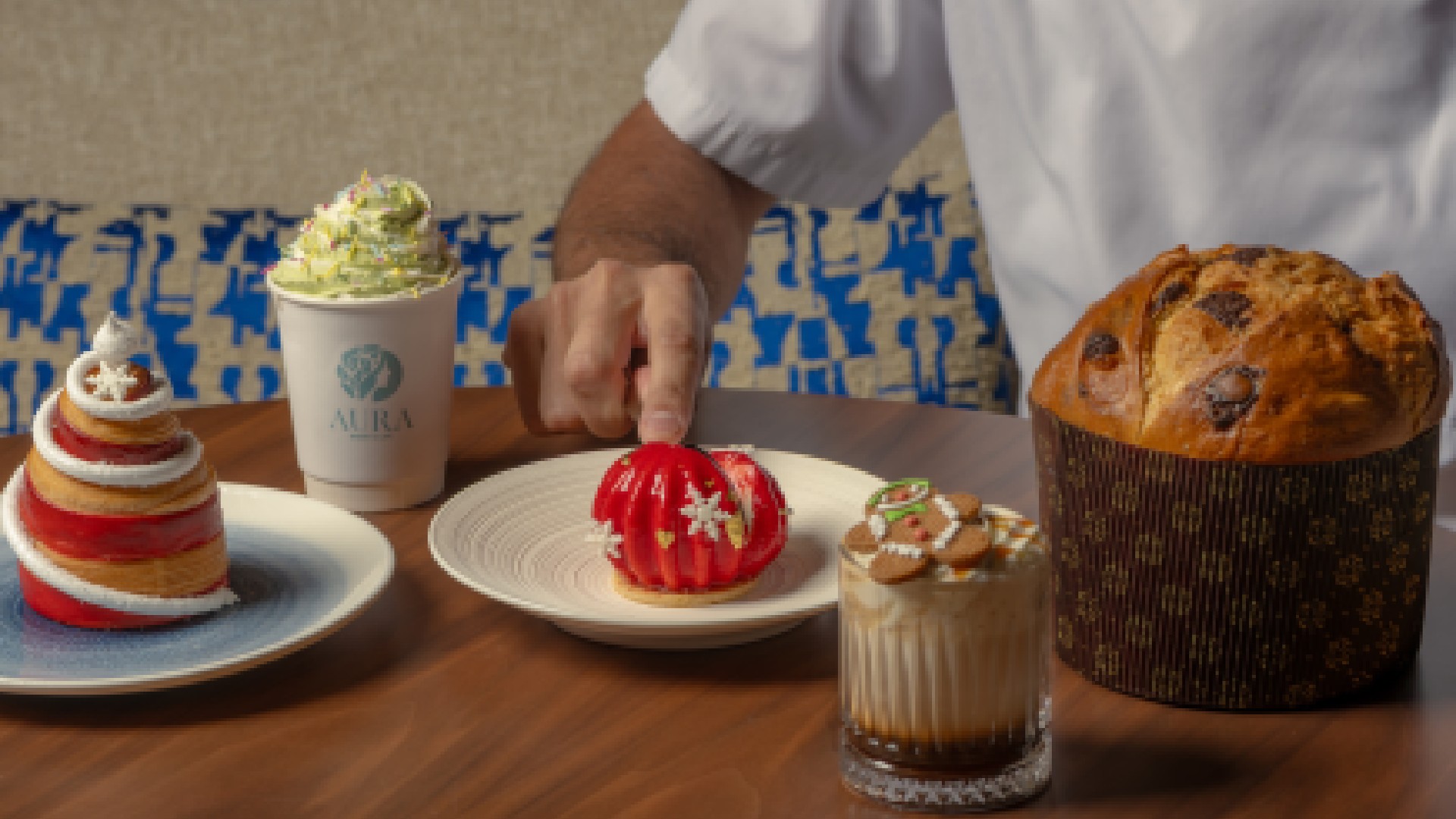 A traditional Italian Panettone cake wrapped in festive paper and ribbon, sitting on a white pedestal.