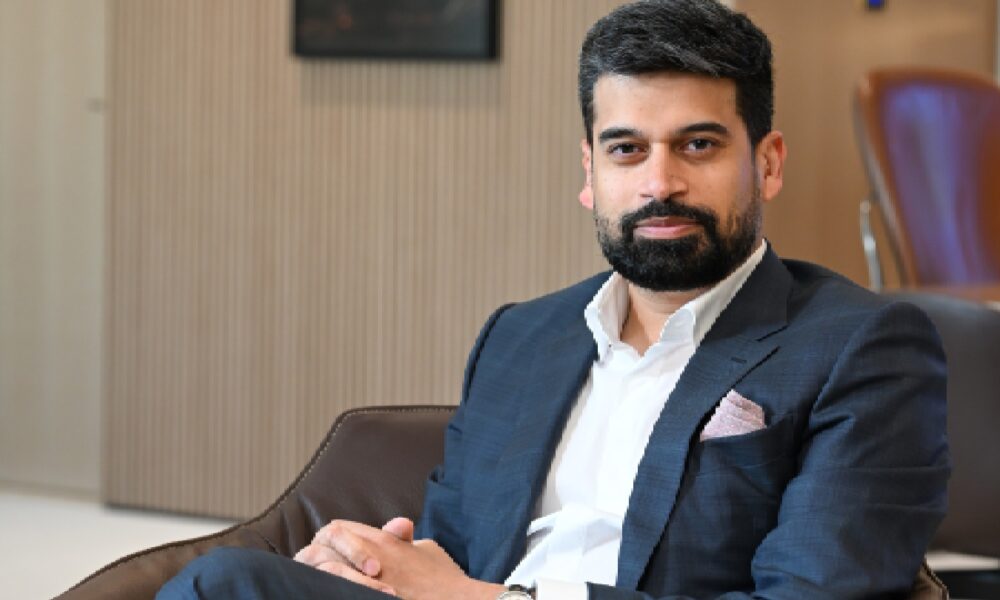 A professional headshot of Mr. Ravi Menon of Sobha Group, a leader in the luxury furniture and real estate division, smiling in a formal setting.
