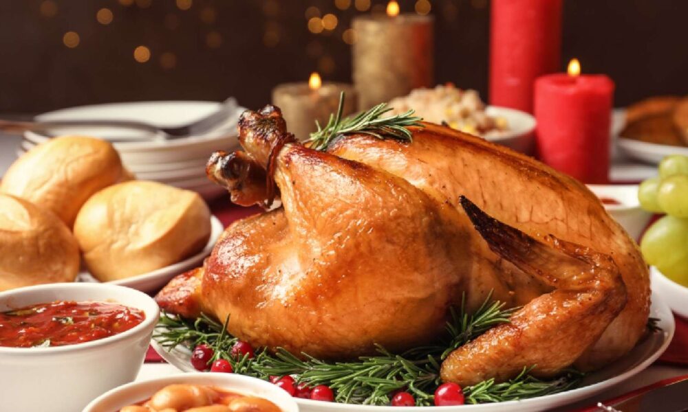 A festive whole roasted turkey from ARCADE EATERY & BAR, served on a platter surrounded by a colorful assortment of roasted root vegetables and classic holiday side dishes.