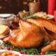 A festive whole roasted turkey from ARCADE EATERY & BAR, served on a platter surrounded by a colorful assortment of roasted root vegetables and classic holiday side dishes.