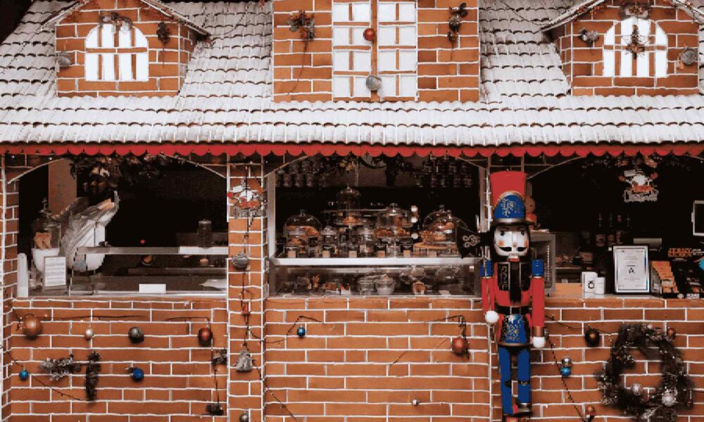 A festive, decorative gingerbread house from MÖVENPICK Jumeirah Lakes Towers, adorned with white icing, candy cane details, and colorful holiday sweets.