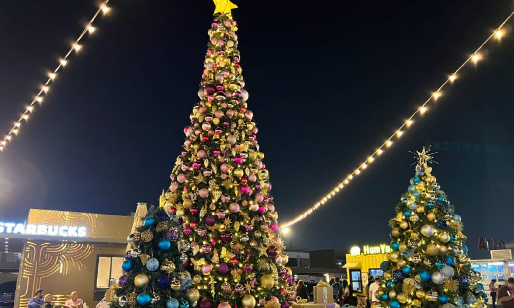 A brightly decorated Santa's Grotto set up on the sand at Kite Beach Dubai, featuring a large, inflatable Santa Claus and colorful festive decorations against the backdrop of the beach.