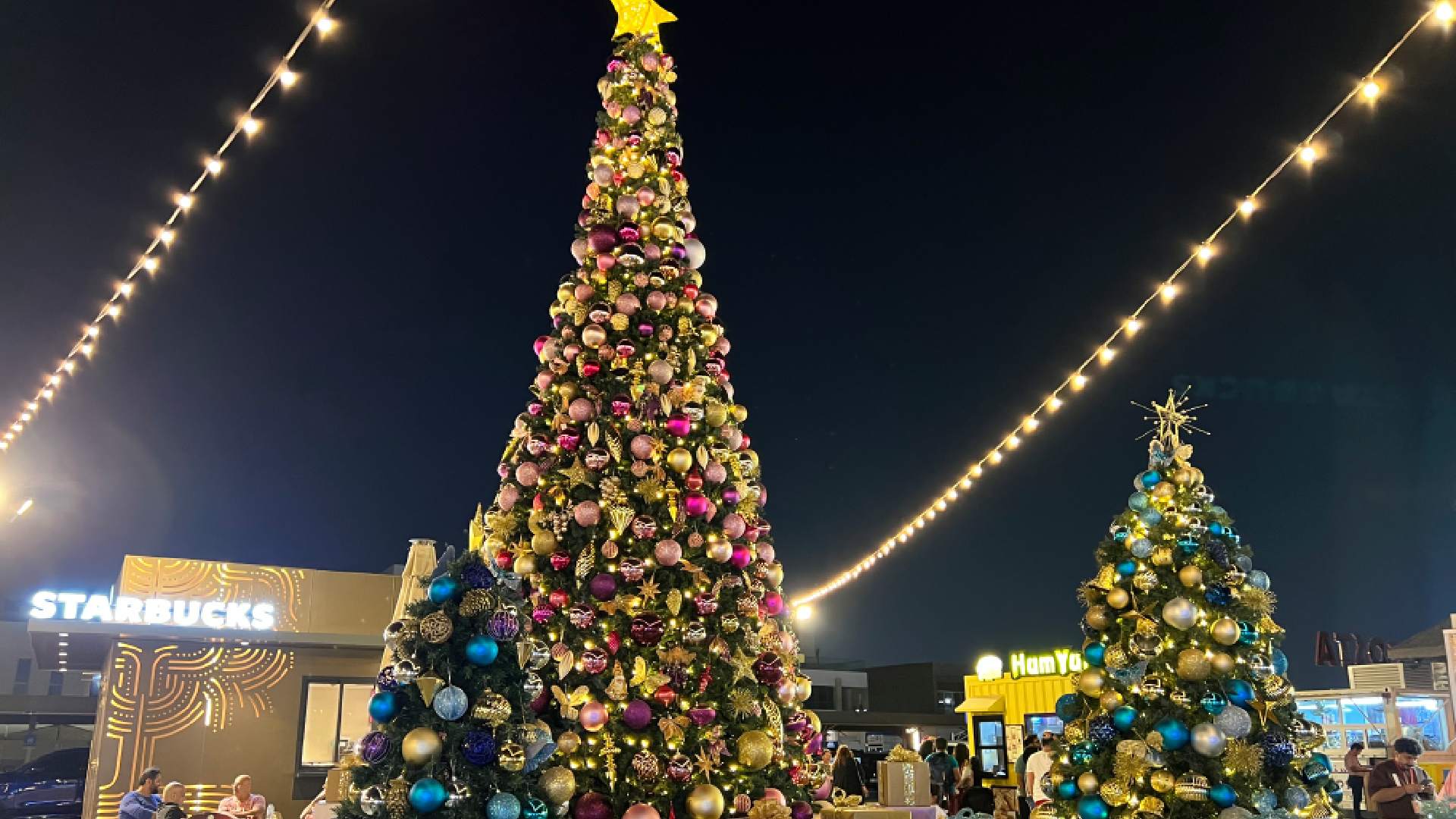 A brightly decorated Santa's Grotto set up on the sand at Kite Beach Dubai, featuring a large, inflatable Santa Claus and colorful festive decorations against the backdrop of the beach.