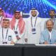 Signing ceremony of a Memorandum of Understanding between Rqeem for Smart Solutions and Torry Harris Business Solutions, with representatives seated at a table signing documents and others standing behind, against a backdrop featuring event branding and digital graphics