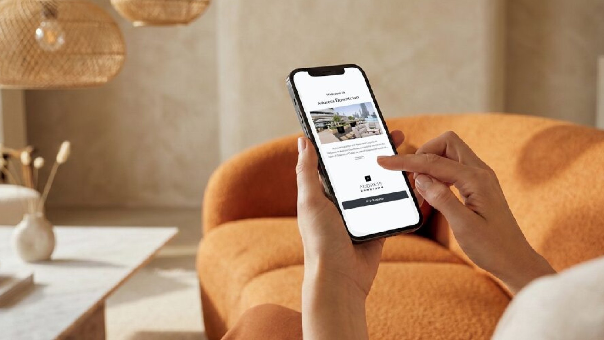 "A close-up, over-the-shoulder view of a person holding a smartphone and using their index finger to interact with the new Address Downtown digital check-in interface