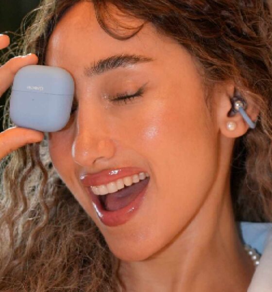 A lifestyle product photograph of the HUAWEI Mate XT ULTIMATE DESIGN, the world’s first commercially available trifold smartphone, being unfolded from its 6.4-inch phone size to its full 10.2-inch 3K display.