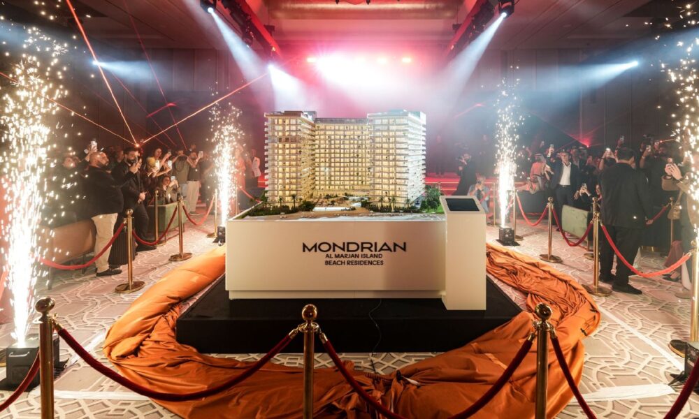 The architectural model for the Mondrian Al Marjan Island Beach Residences displayed at an event with bright lights and indoor pyrotechnic sparklers.