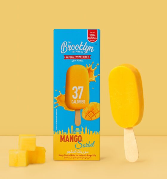 A close-up shot of The Brooklyn Creamery's 37-calorie Mango Sorbet Bar, showing the bright orange sorbet and a partially peeled wrapper on a white background.