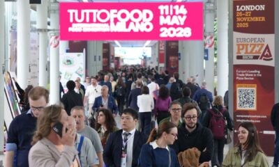 An aerial view of the crowded, expansive halls of the TUTTOFOOD trade show in Milan, showing rows of exhibitor booths and numerous professional visitors walking the aisles, highlighting the event's scale