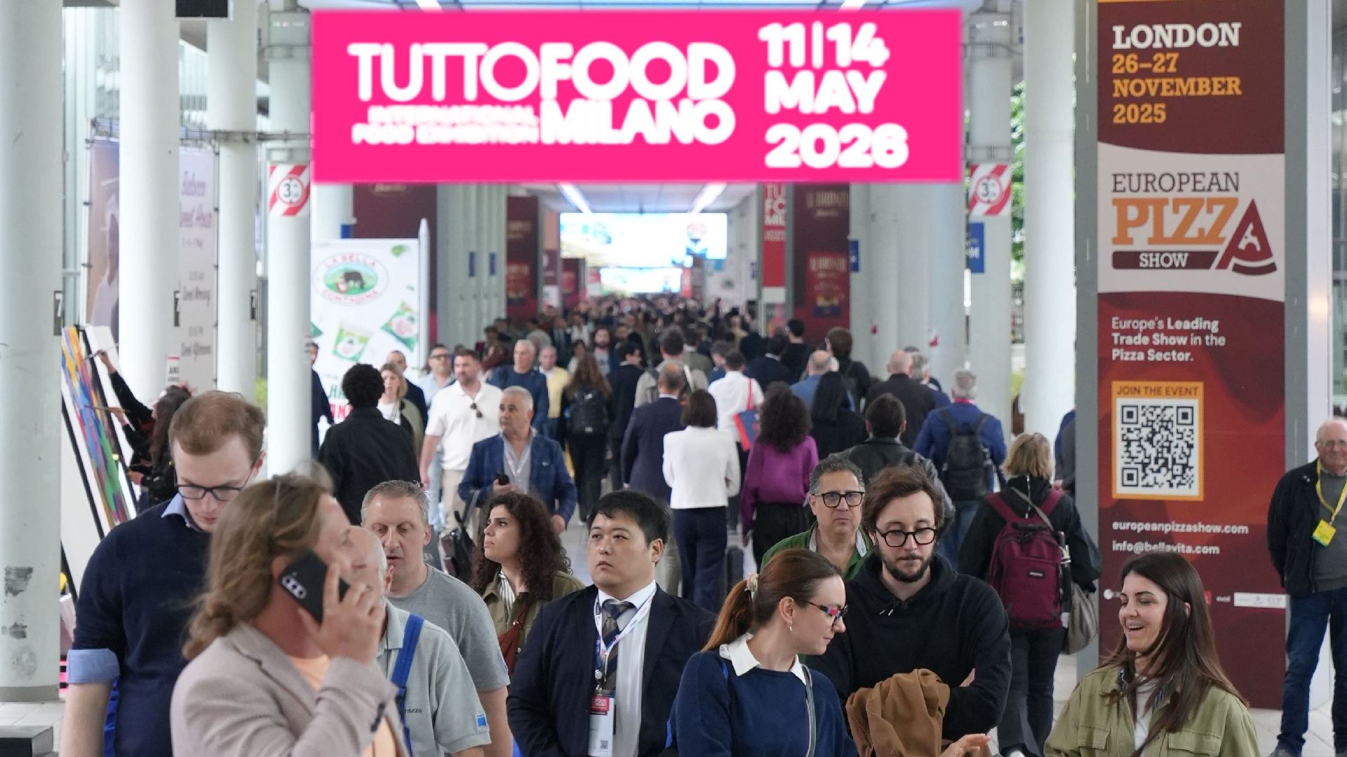 An aerial view of the crowded, expansive halls of the TUTTOFOOD trade show in Milan, showing rows of exhibitor booths and numerous professional visitors walking the aisles, highlighting the event's scale