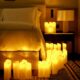 A cozy hotel bedroom at Sofitel featuring a white bed with crisp linens, surrounded by numerous glowing pillar candles arranged on the floor and nightstand, creating a warm and intimate ambiance.