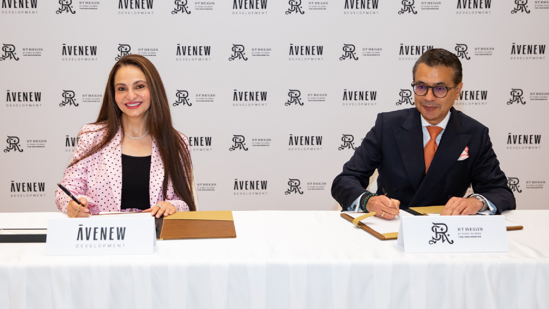 A group of four business professionals, two women and two men, are formally seated at a conference table, posing for a photograph during a signing ceremony or press event.