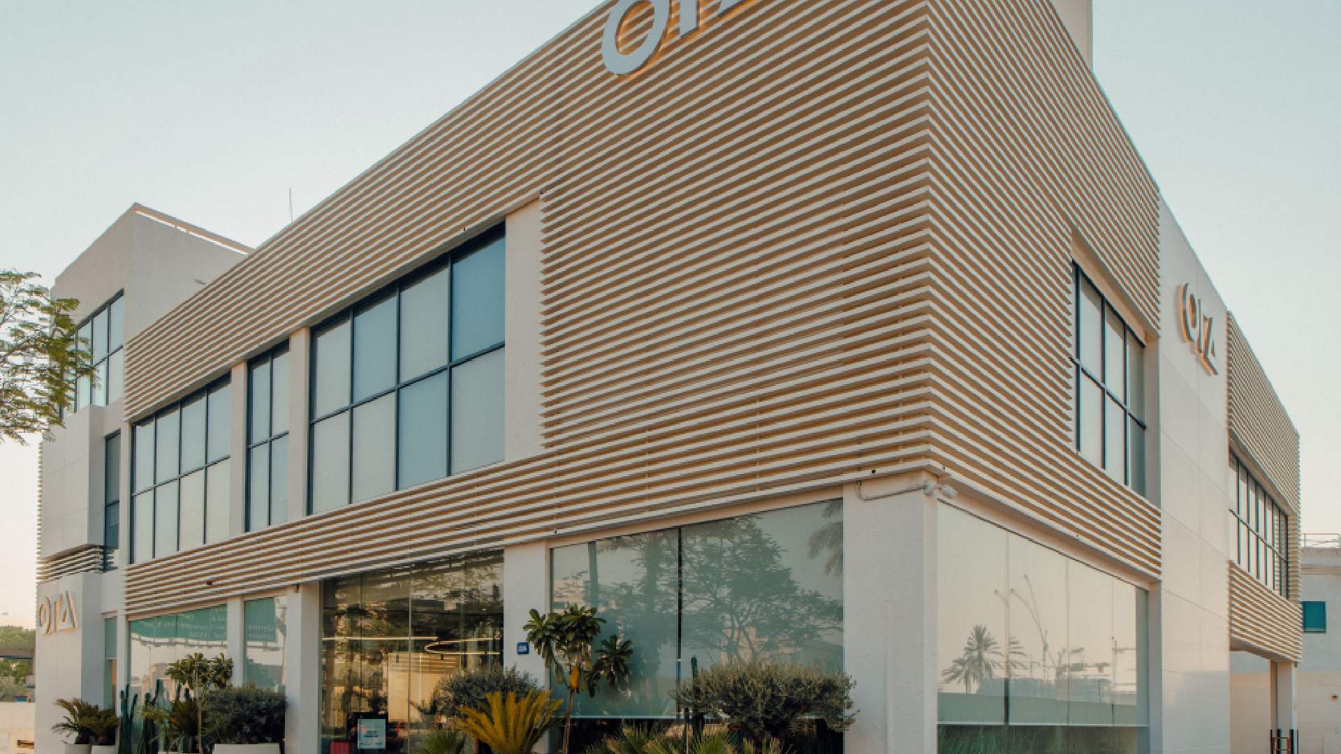 A man in a dark suit is speaking passionately while holding a microphone on a stage in front of a large, diverse audience seated in a dark, formal auditorium.