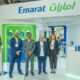 Four Emarat employees, two men and two women, pose in front of the branded Emarat exhibition booth displaying lubricant products.
