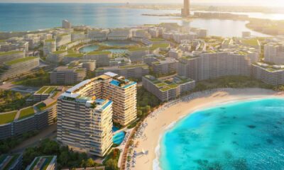 A high-angle architectural rendering of the Elevate Mondrian Al Marjan Island development, showing the massive resort complex, curved towers, and extensive beachfront facilities