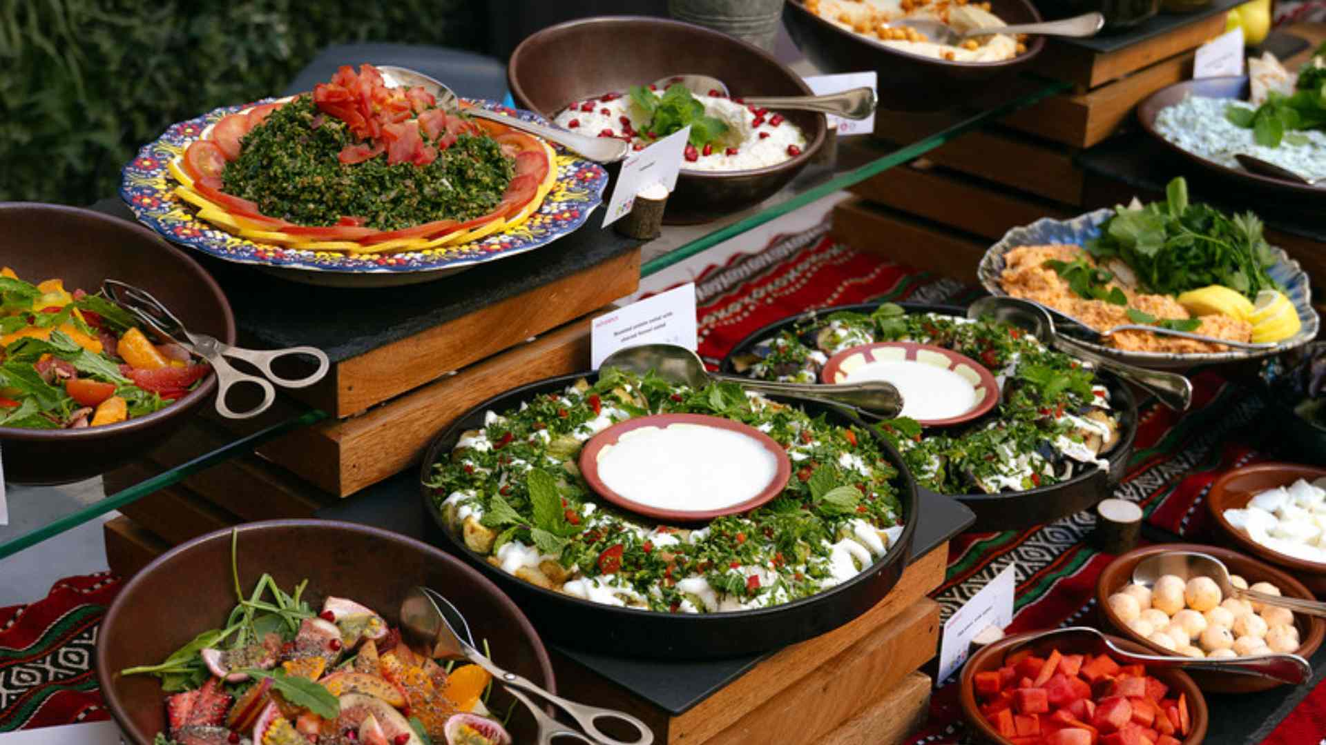 A vibrant Ramadan buffet display at Mövenpick Hotel featuring assorted Middle Eastern salads, fresh vegetables, mezze dishes, and bowls of colorful ingredients arranged neatly on wooden risers and decorative tableware.
