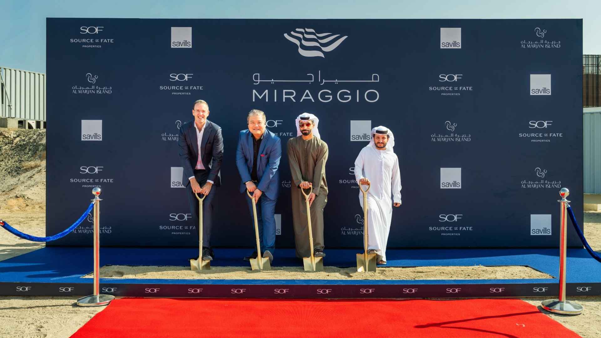 Source of Fate officials and partners participate in a ceremonial ground‑breaking for the Miraggio development on Al Marjan Island, holding shovels on a red carpeted site in front of a branded Miraggio and Source of Fate backdrop.